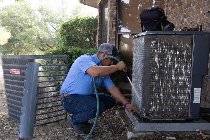 HVAC technician inspecting an older outdoor condenser to diagnose cooling problems and determine whether AC repair in California is appropriate.