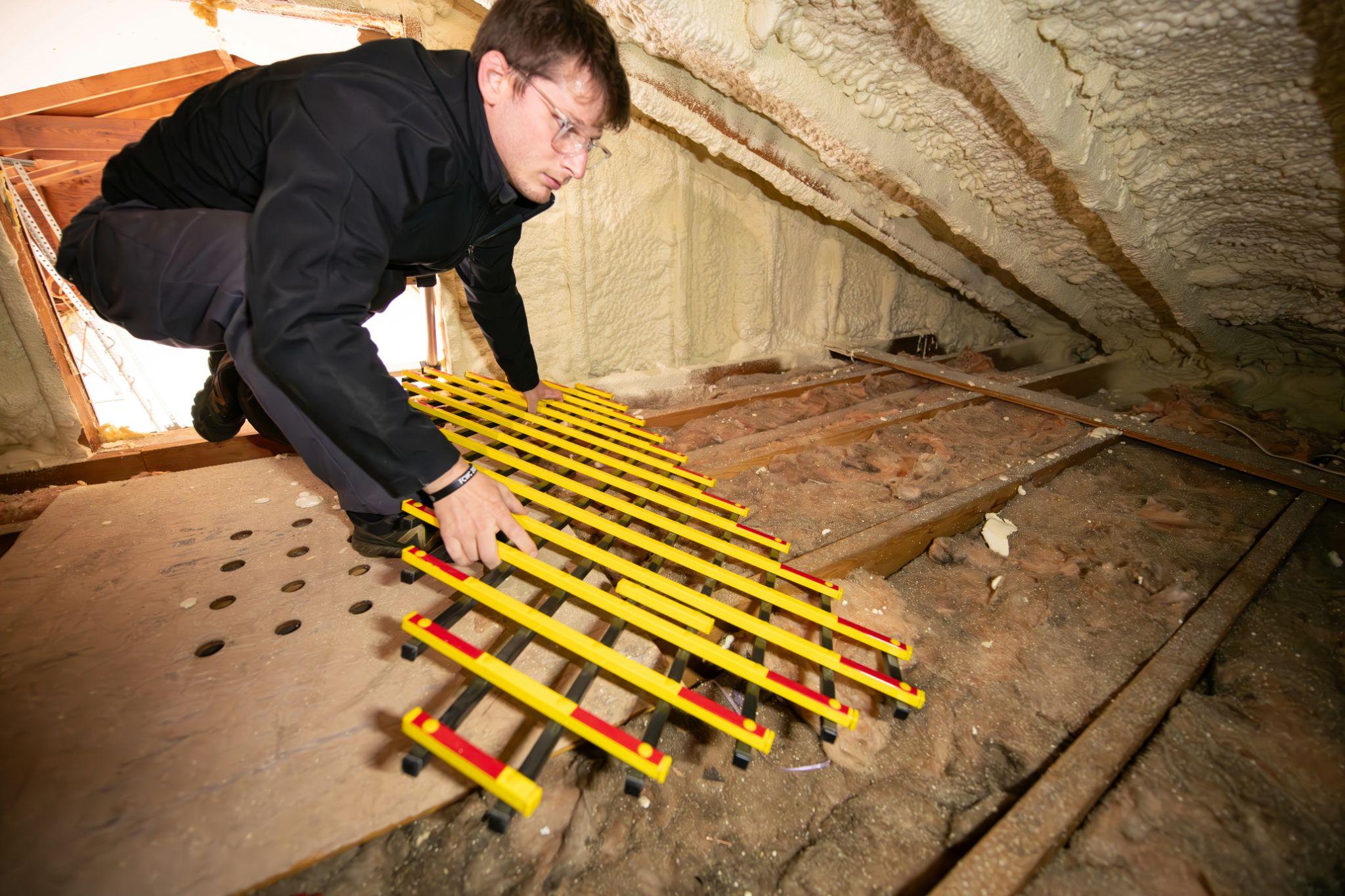 A technician inspects spray foam insulation in an attic, illustrating attic insulation in Turlock.