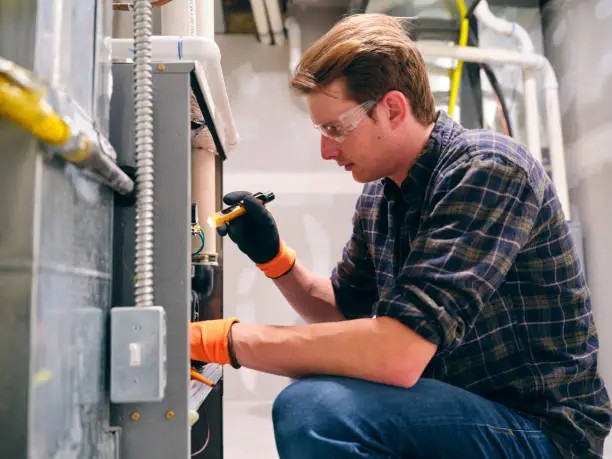 Professional servicing a residential furnace during routine heating system maintenance.