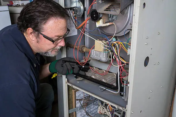 A technician looking over a gas furnace during routine furnace maintenance in Turlock.