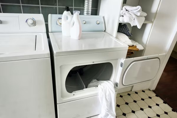 White washer and dryer set in a home laundry room with dryer door open