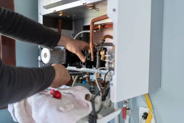 HVAC technician performing furnace repair in California by inspecting internal heating system components.