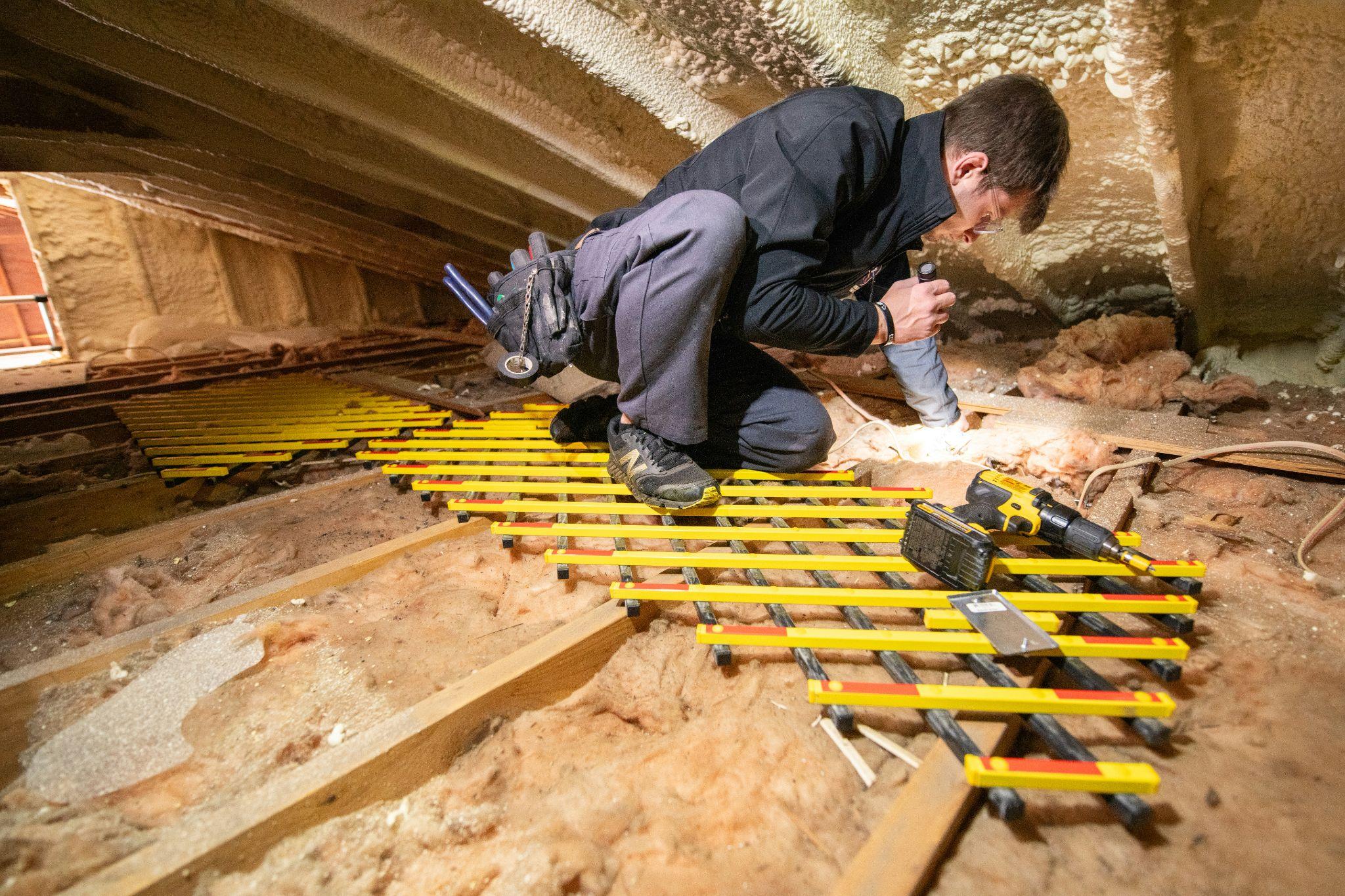 A worker is carrying out attic insulation installation in California to improve the space.