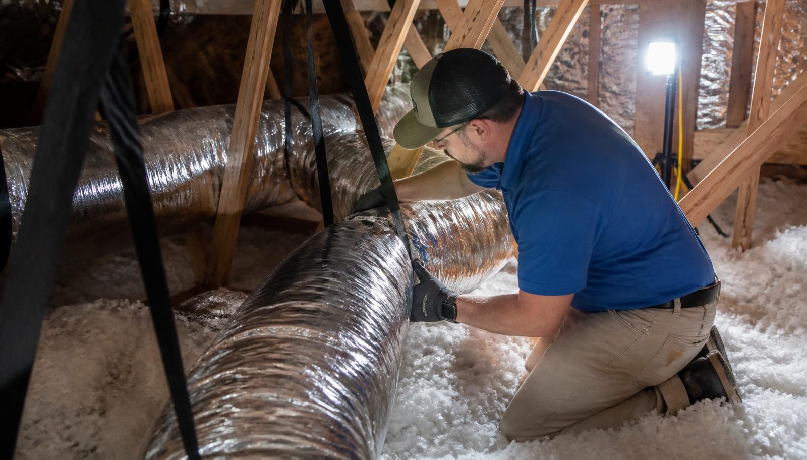 HVAC technician inspecting flexible attic ductwork and insulation in a Central Valley home