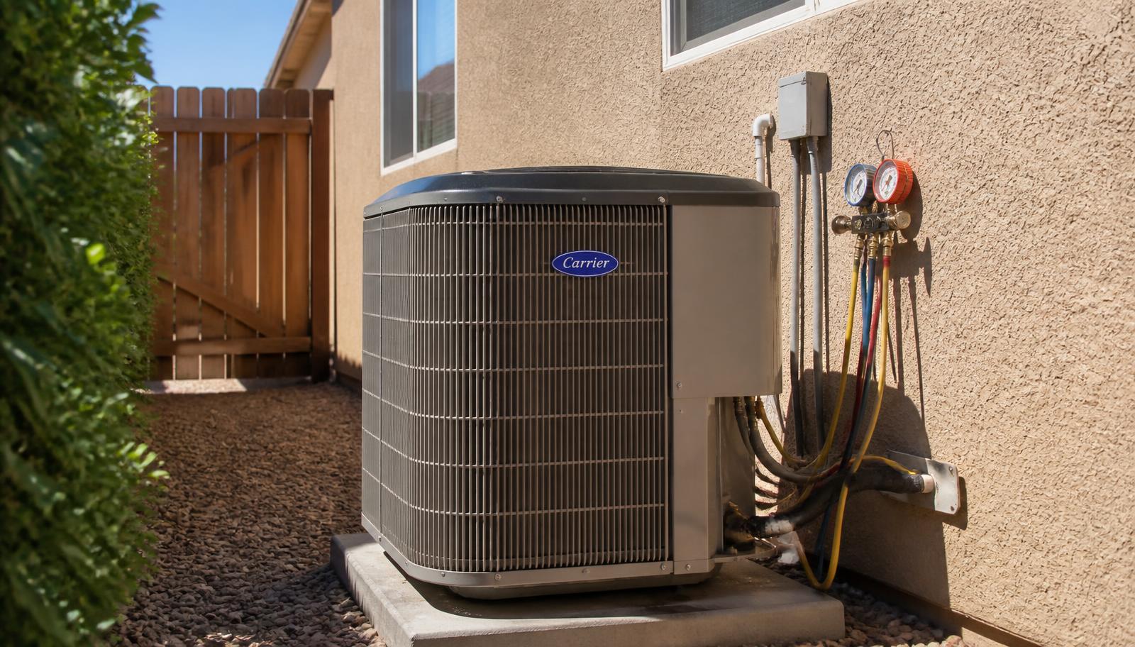 Outdoor air conditioner condenser beside a Modesto stucco home on a hot summer day