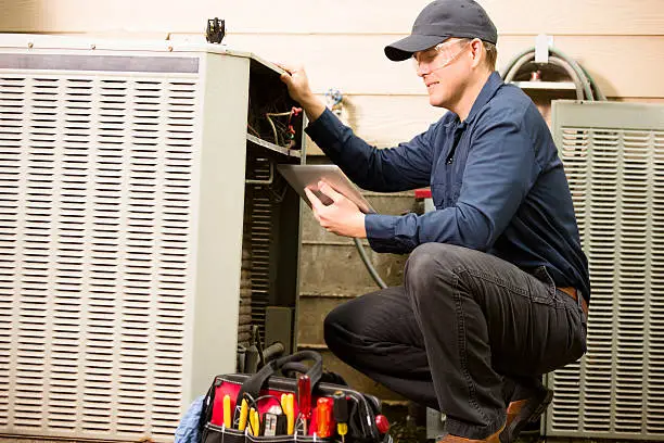 Technician inspecting an outdoor air conditioner during HVAC repair services in California