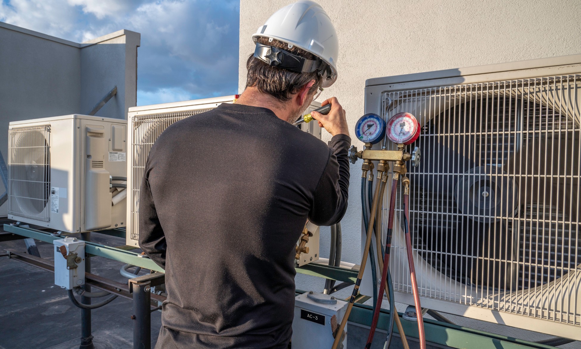 Technician inspecting an outdoor air conditioning unit as part of professional HVAC services in California.