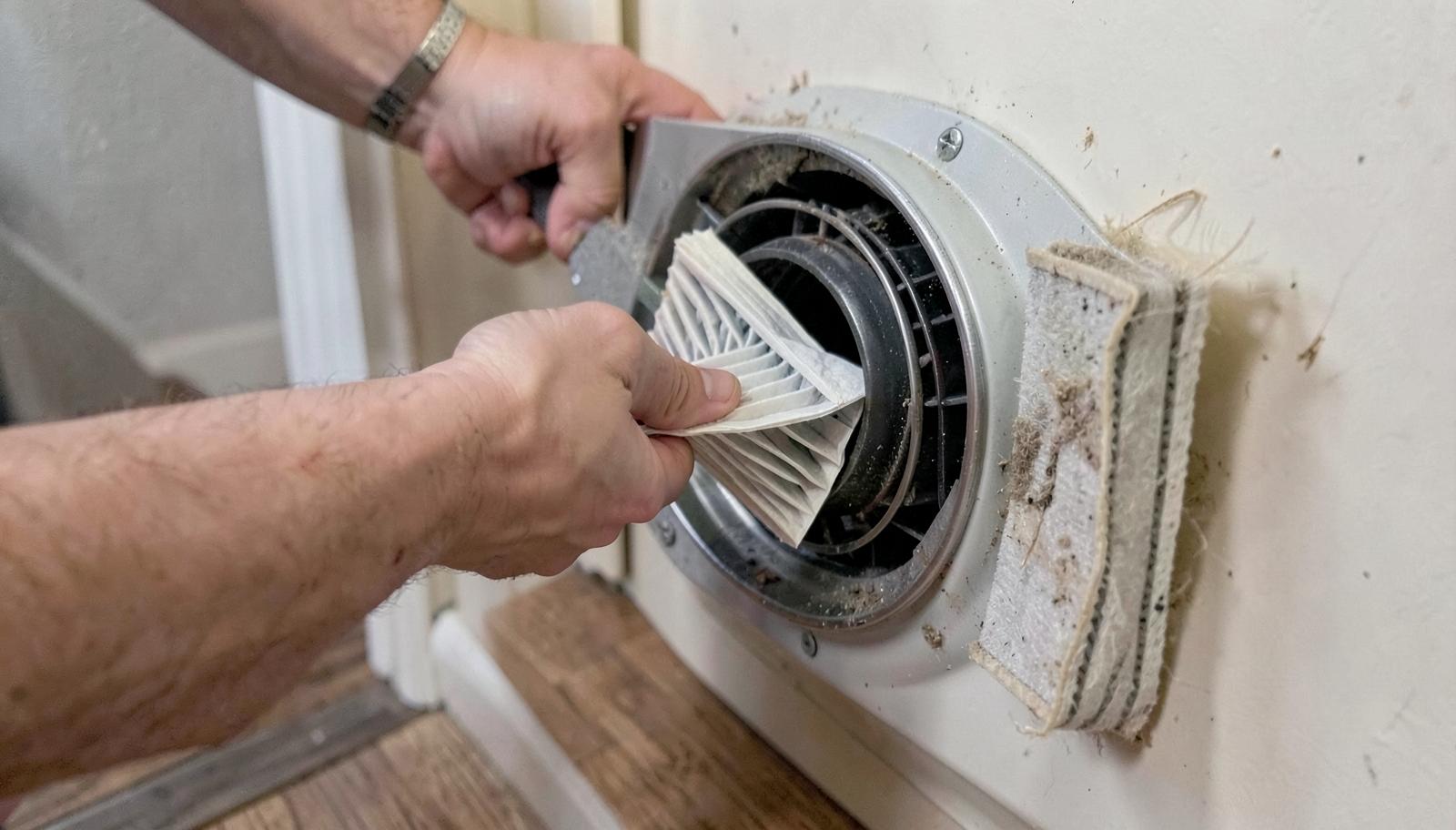 Homeowner replacing a dusty pleated air filter in a home HVAC return vent